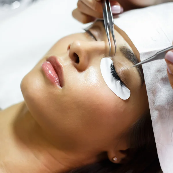 Eyelash extension procedure - master and a client in a beauty salon