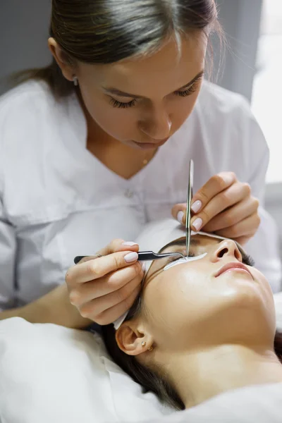 Eyelash extension procedure - master and a client in a beauty salon