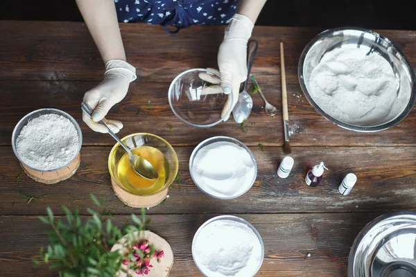 Preparation of bath bombs. Ingredients and floral decor on a wooden vintage table.