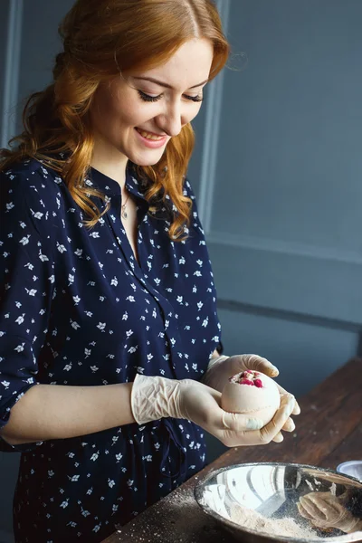 Young woman prepare bath bombs. Ingredients and floral decor on a wooden vintage table.