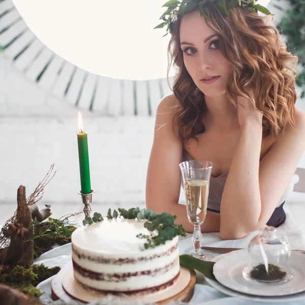 Wedding cake over decor on a table in ecological natural style. Bride sitting by the table with decorative composition