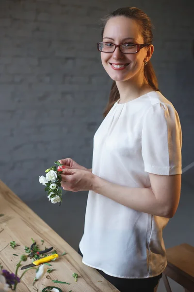 Florist at work: woman making floral composition of different flowers