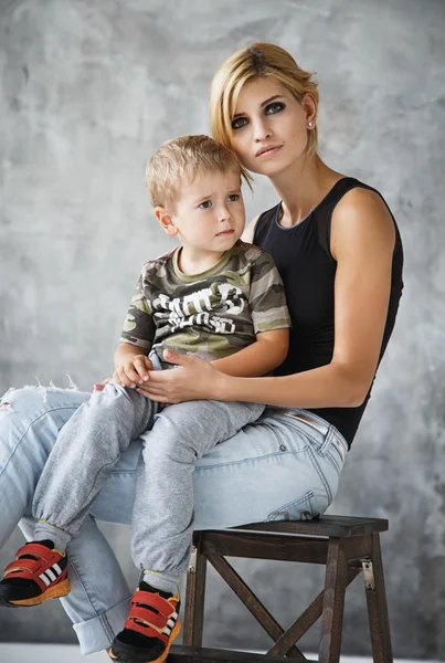 Beautiful blonde stylish young woman and her son in studio photoshoot