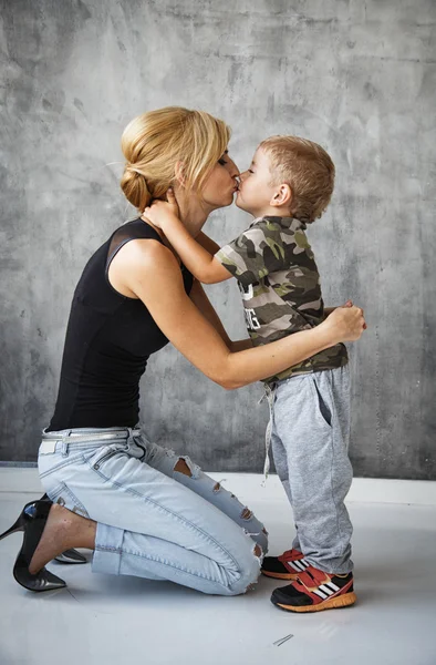 Beautiful blonde stylish young woman and her son in studio photoshoot