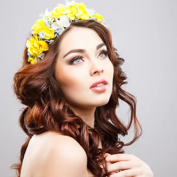 Close-up portrait of beautiful young woman with perfect make-up and hair-style with flowers in hair