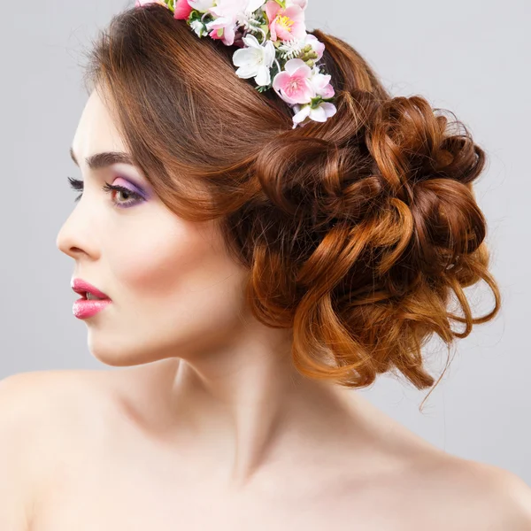 Close-up portrait of beautiful young woman with perfect make-up and hair-style with flowers in hair