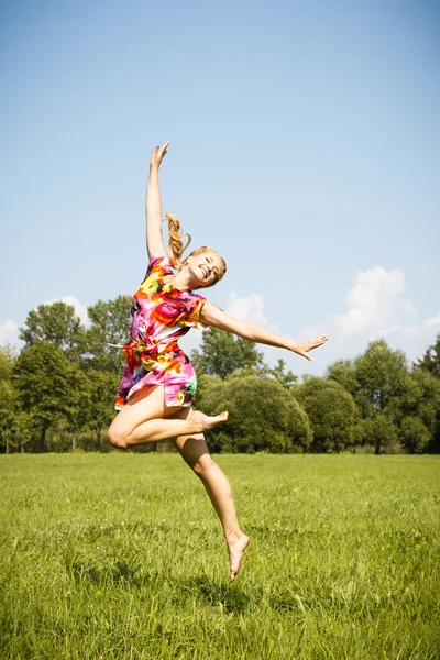 Pretty blonde young girl jumping in a park in a summer