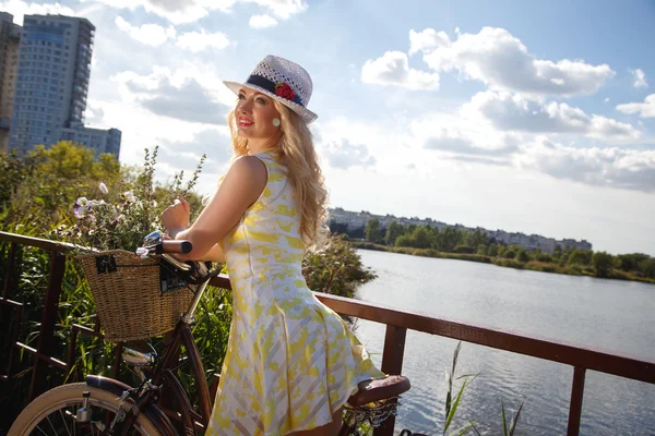 Beautiful sweet blonde woman walks with bicycle near skyscrapers