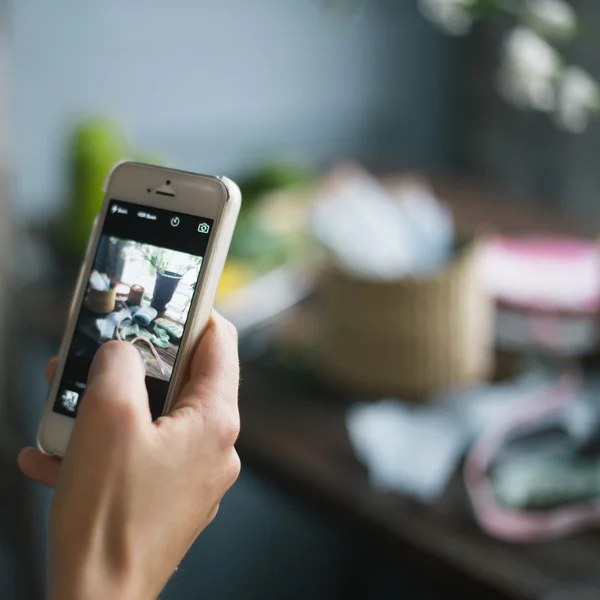 Florist at work: pretty young blond woman making photo on her mobile phone (smart phone)