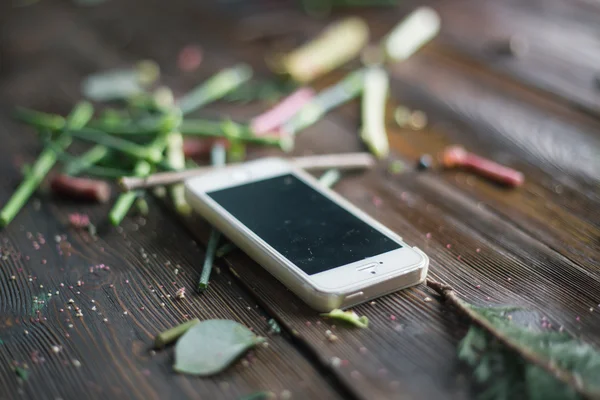 Florist workplace: mobile phone (smart phone) and flowers and accessories on a vintage wooden table. soft focus