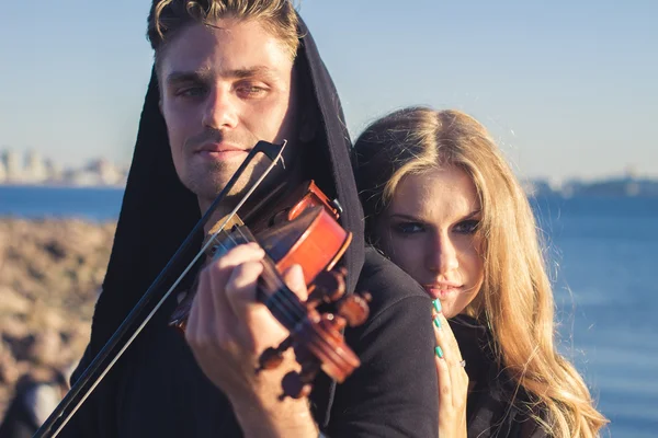 Beautiful couple violinist and young woman together near sea bay