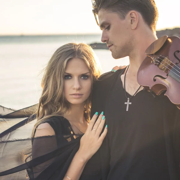 Beautiful couple violinist and young woman together near sea bay
