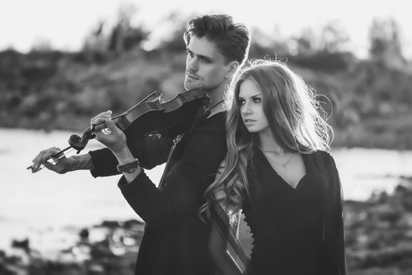 Beautiful couple violinist and young woman together near sea bay