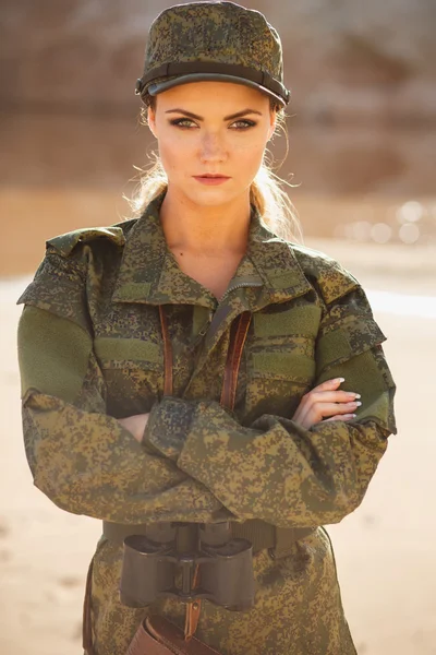 Gorgeous young woman in a Military costume on the background of a dessert