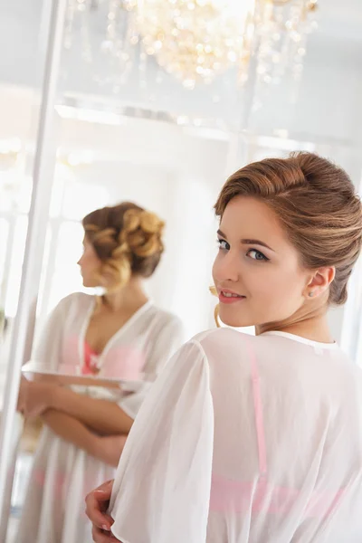 Beautiful bride in white lingerie looking at mirror in a morning