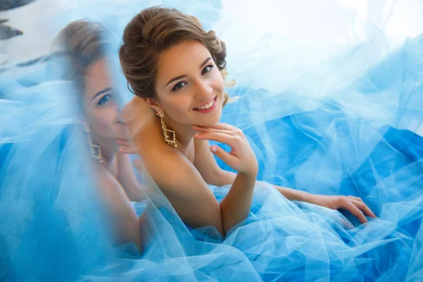 Beautiful bride in gorgeous blue dress Cinderella style in a morning near mirror
