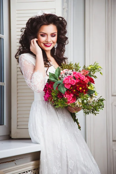 Close-up portrait of gorgeous beautiful bride in white dress with amazing hair style and make up, holding bouquet