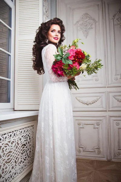 Close-up portrait of gorgeous beautiful bride in white dress with amazing hair style and make up, holding bouquet