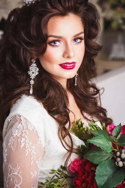 Close-up portrait of gorgeous beautiful bride in white dress with amazing hair style and make up, holding bouquet