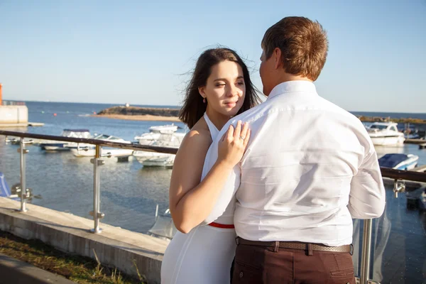 Beautiful couple man and woman walks together near yacht in a summer day