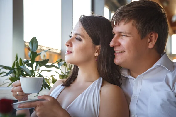Pretty young brunette woman in white dress and a young man resting together in a restaurant in a summer day