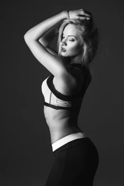 Close-up portrait of sport young blonde woman over dark background isolated. Fitness model. Black and white photo