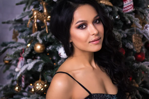 Portrait of elegant young woman in evening dress over christmas background, fashion beauty photo