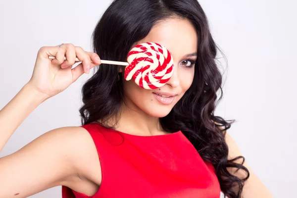 Pretty young woman in red dress with a lollipop