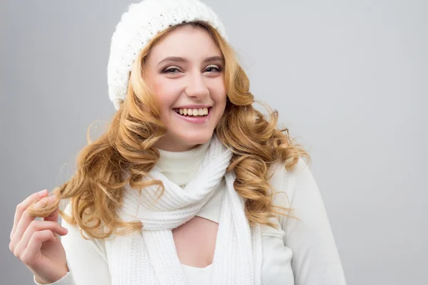 Close-up portrait of a blonde girl in a warm white pullover and hat isolated on white background
