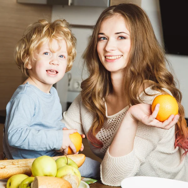 Pretty blonde young woman and her little son together in a kitchen