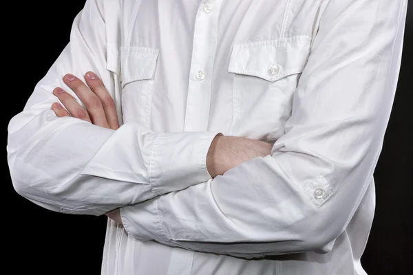 Male hands in white shirt folded on his chest closeup