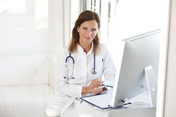 Doctor sitting at computer in exam room