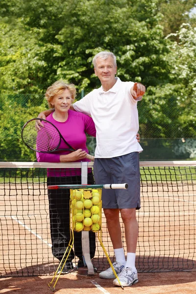 Senior couple standing at tennis court