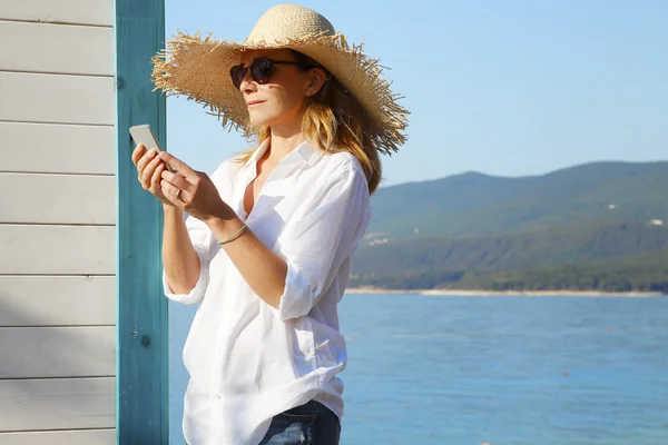 Businesswoman by sea and using phone
