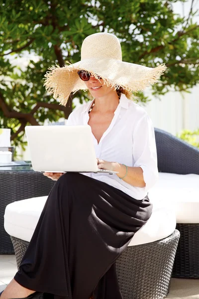 Woman in garden and working on laptop