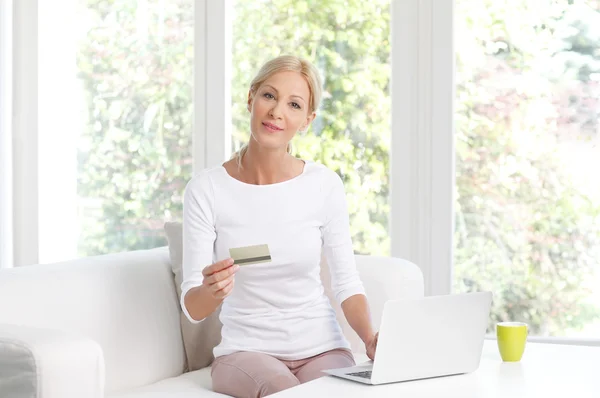 Woman holding credit card in front of laptop