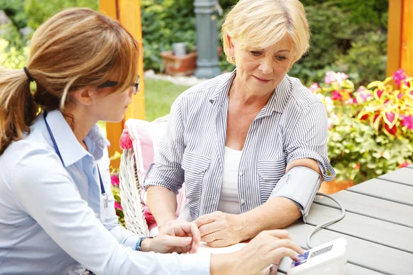 Home caregiver measuring blood pressure