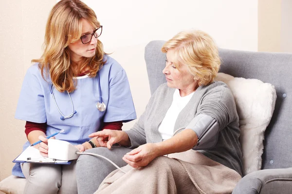 Nurse checking blood pressure of elderly woman.