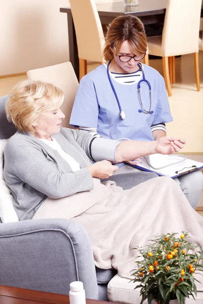 Nurse checking patient\'s blood pressure.