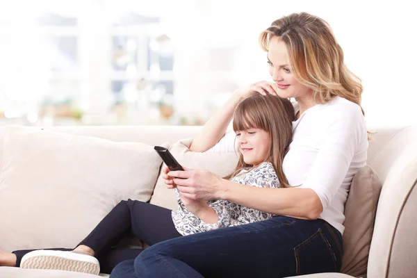 Happy mother and daughter watching tv