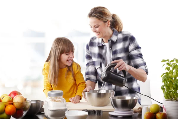 Girl and her mother mixing the ingredients.