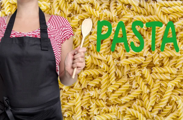 Pasta cook holding wooden spoon in front of noodle background