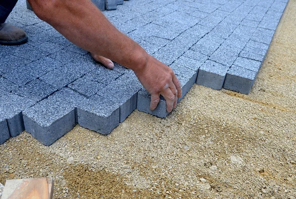 A worker made a sidewalk from bricks.