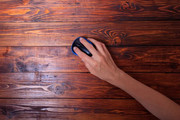 Woman\'s hand holding pc wireless mouse on dark wooden table