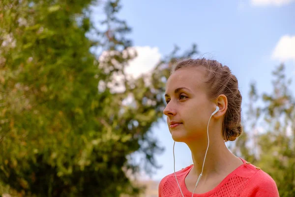 Woman listening music with headset in green park