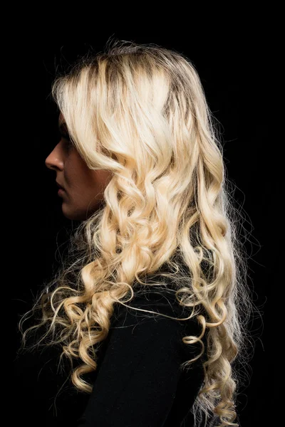 Profile portrait of a blonde woman on black
