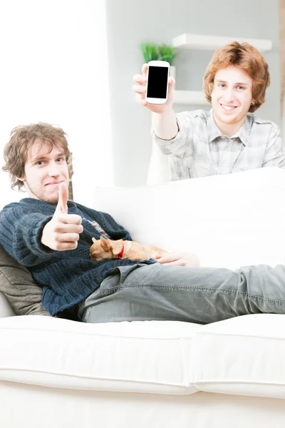 Handsome twin brothers relaxing with phone and dog