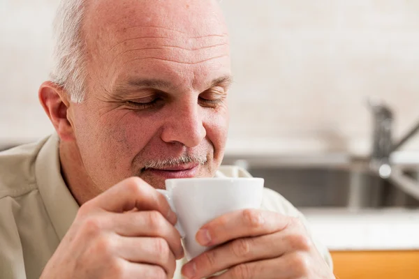 Man with eyes close holding coffee up to his nose