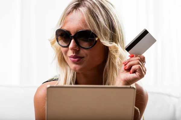 Grinning woman with credit card and tablet