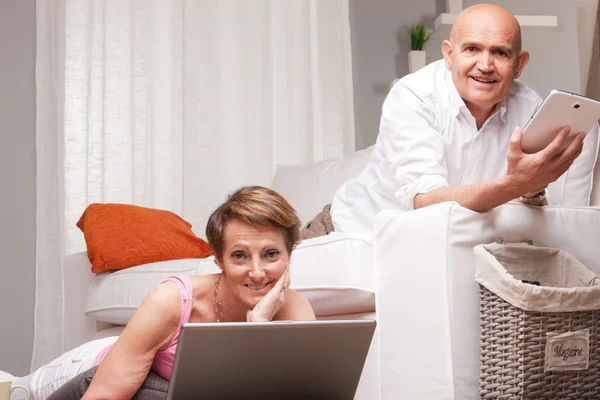 Mature couple reading news in digital devices